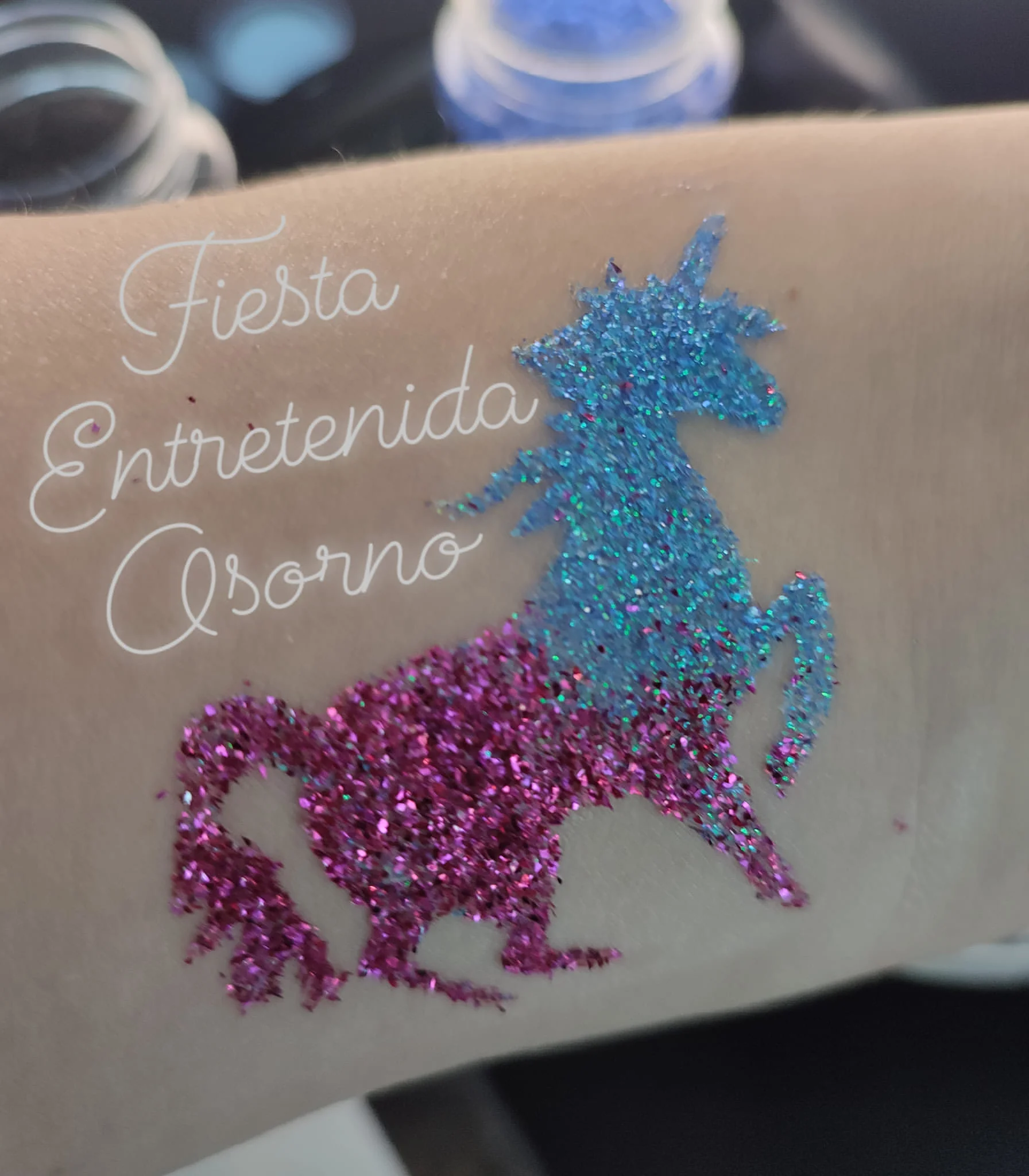 Fotografía original de tatuaje de glitter con forma de unicornio en tonos azul y rosado